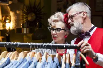 Quirky vintage couple looking at clothes rail in antiques and vintage emporium