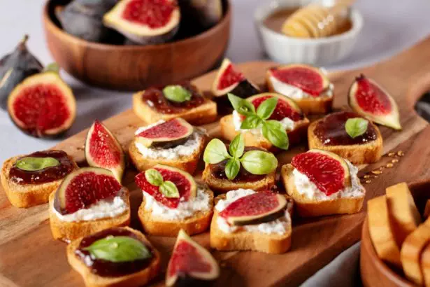 Toasts with figs, ricotta and fig marmalade sprinkled with honey on wooden board