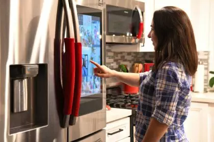 Modern technology. Young millennial woman using smart technology on a refrigerator
