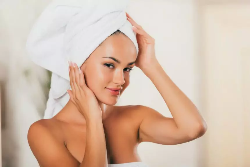 young smiling woman correcting towel on head at spa salon