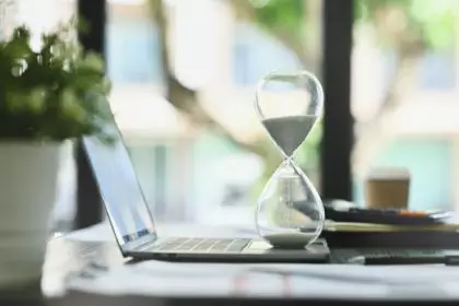 Close up view of hourglass on office desk measuring time. Time management concept