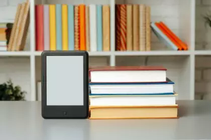 E-book reader on table against book shelves