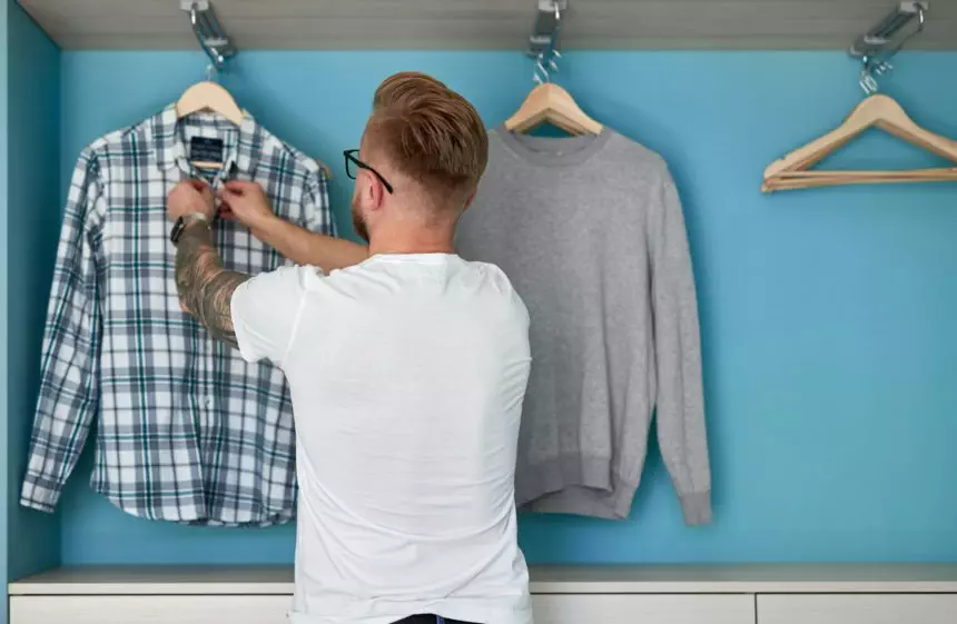 Man organizing garments in wardrobe