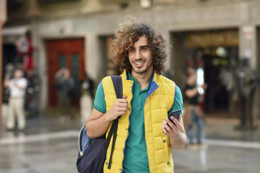 Spain, Granada, portrait of smiling young tourist with backpack discovering the city