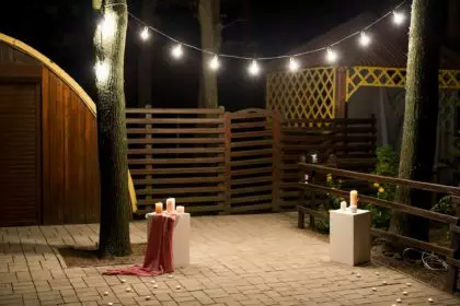 Garden with a wooden gazebo with lights, candles at night at a wedding