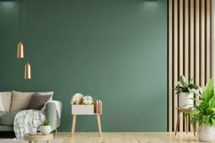 Green sofa with table on green wall and wooden flooring.