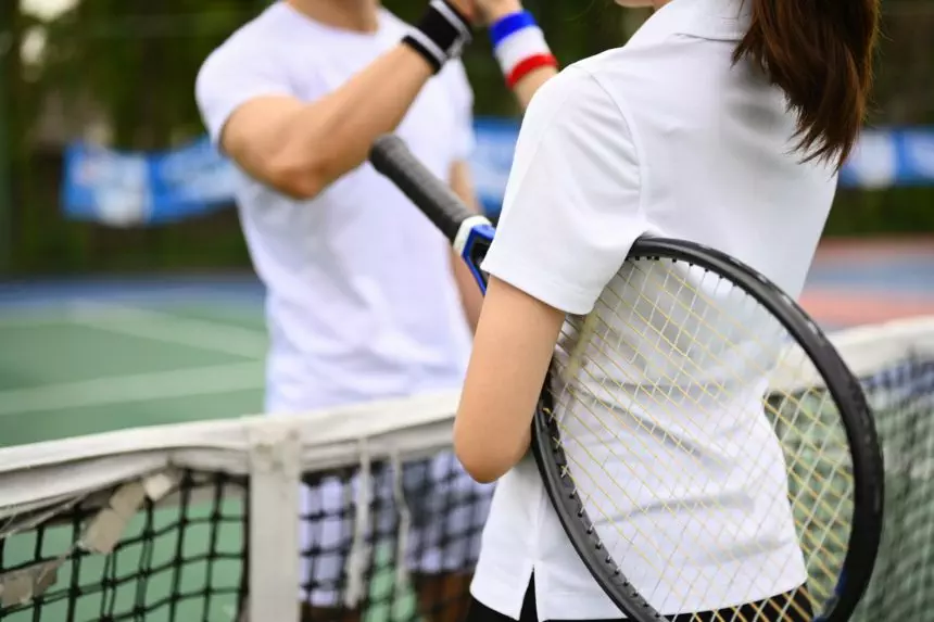 Two young tennis players in sportswear greeting before a tennis match.