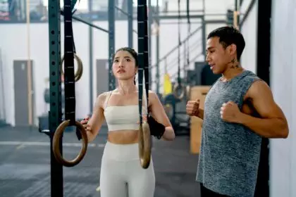 Asian coach or trainer man help and support sport woman to exercise with loop in fitness gym