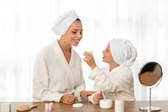 Mother and daughter in bathrobes doing skin care routine at home