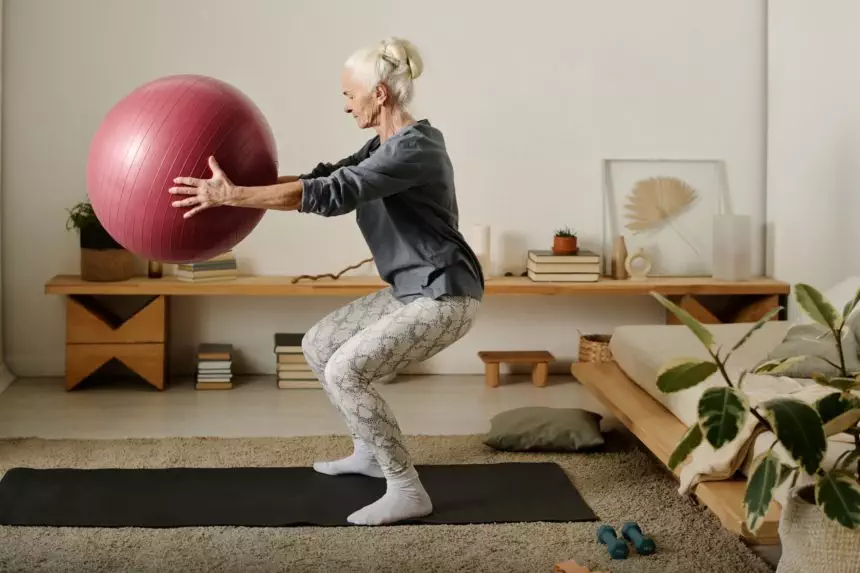 Aged woman doing squats with fitball