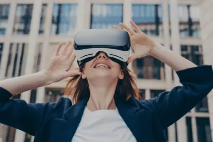 Immersed woman looking up in virtual reality while wearing portable VR, standing on city street