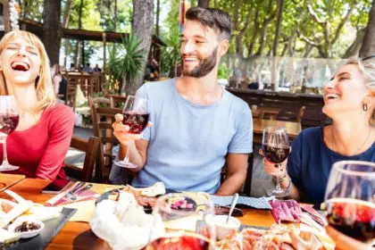 Millenial people having fun drinking red wine glasses at lunch party on sunny day